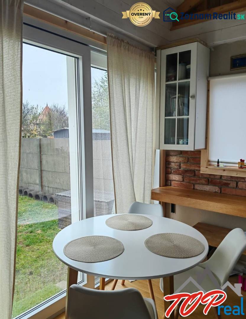 Jídelní kout v rodinném domě s podlahou s dřevěným dekorem, cihlovou stěnou a velkými okny.