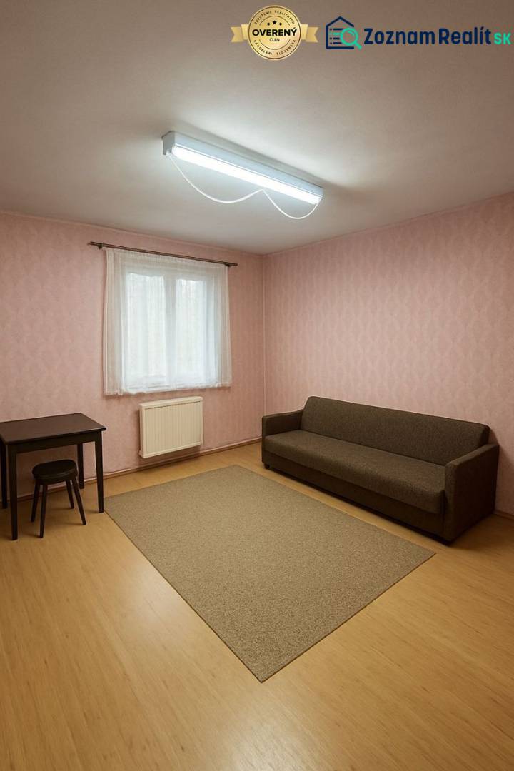 Pokoj v rodinném domě s hnědou pohovkou, stolem a podlahou s dřevěným dekorem.