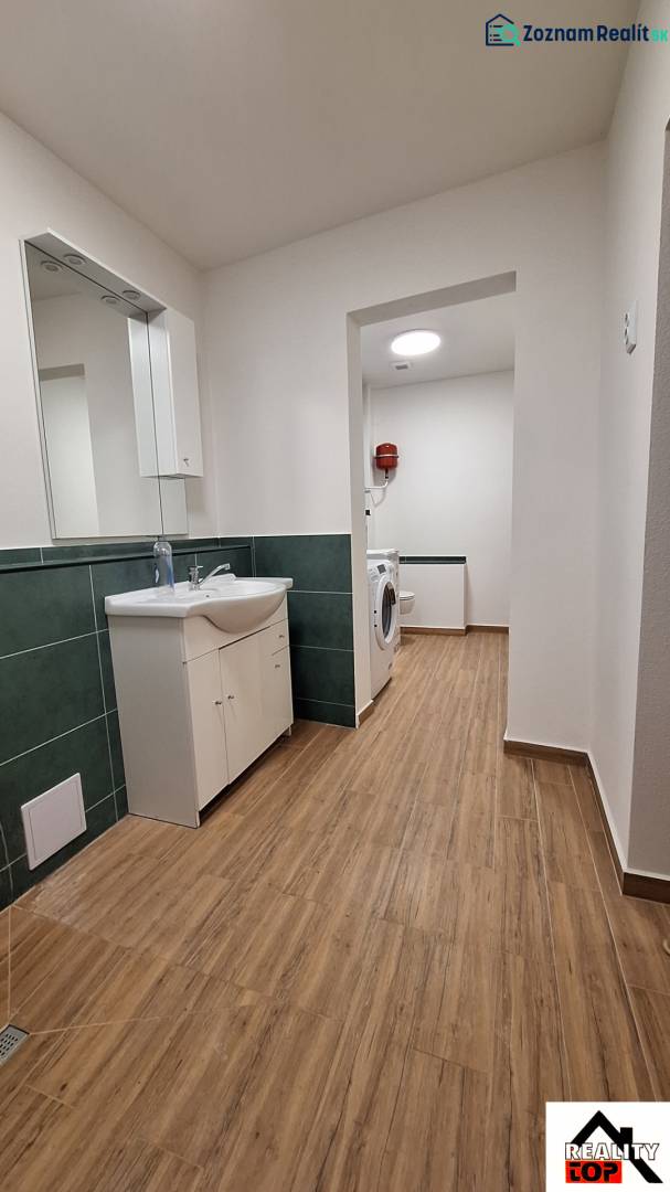 Koupelna v rodinném domě s podlahou s dřevěným dekorem a pračkou.