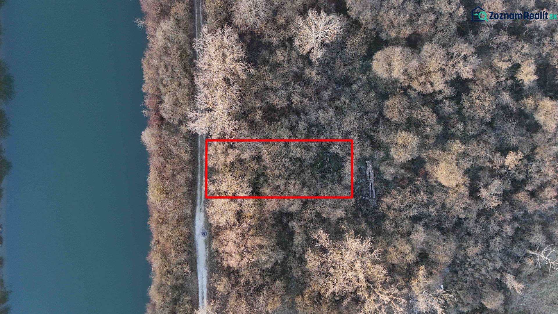 Letecký pohled na rekreační pozemky v Nové Vsi nad Váhem, obklopené lesem a řekou.