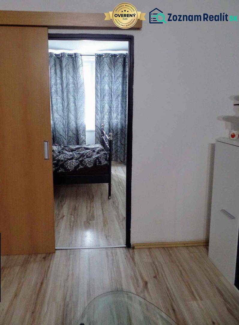 Interiér s podlahou s dřevěným dekorem, posuvnými dveřmi a černobílými závěsy v 3-pokojovém bytě.