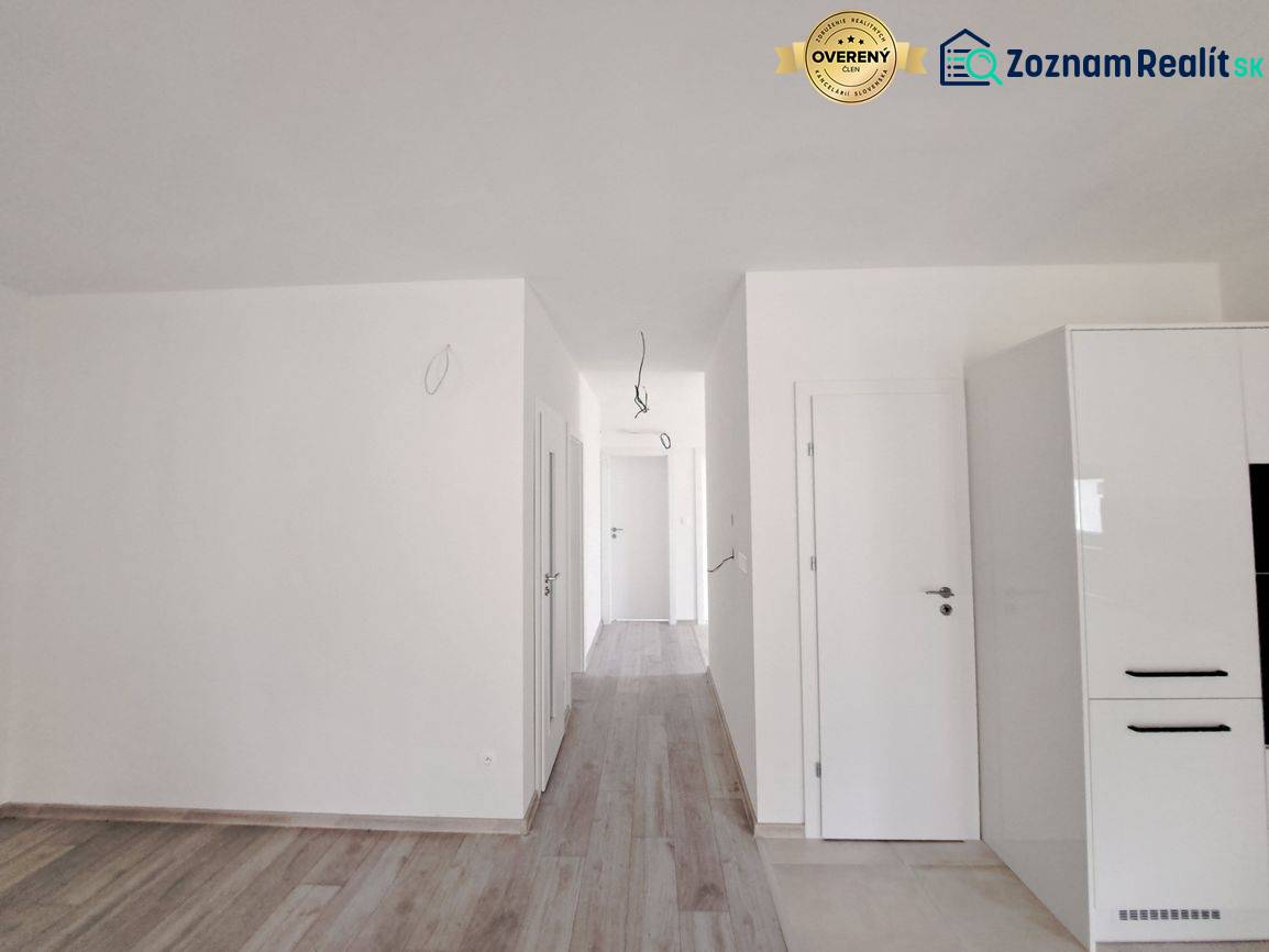 Světlý interiér rodinného domu s podlahou s dřevěným dekorem a bílými stěnami.