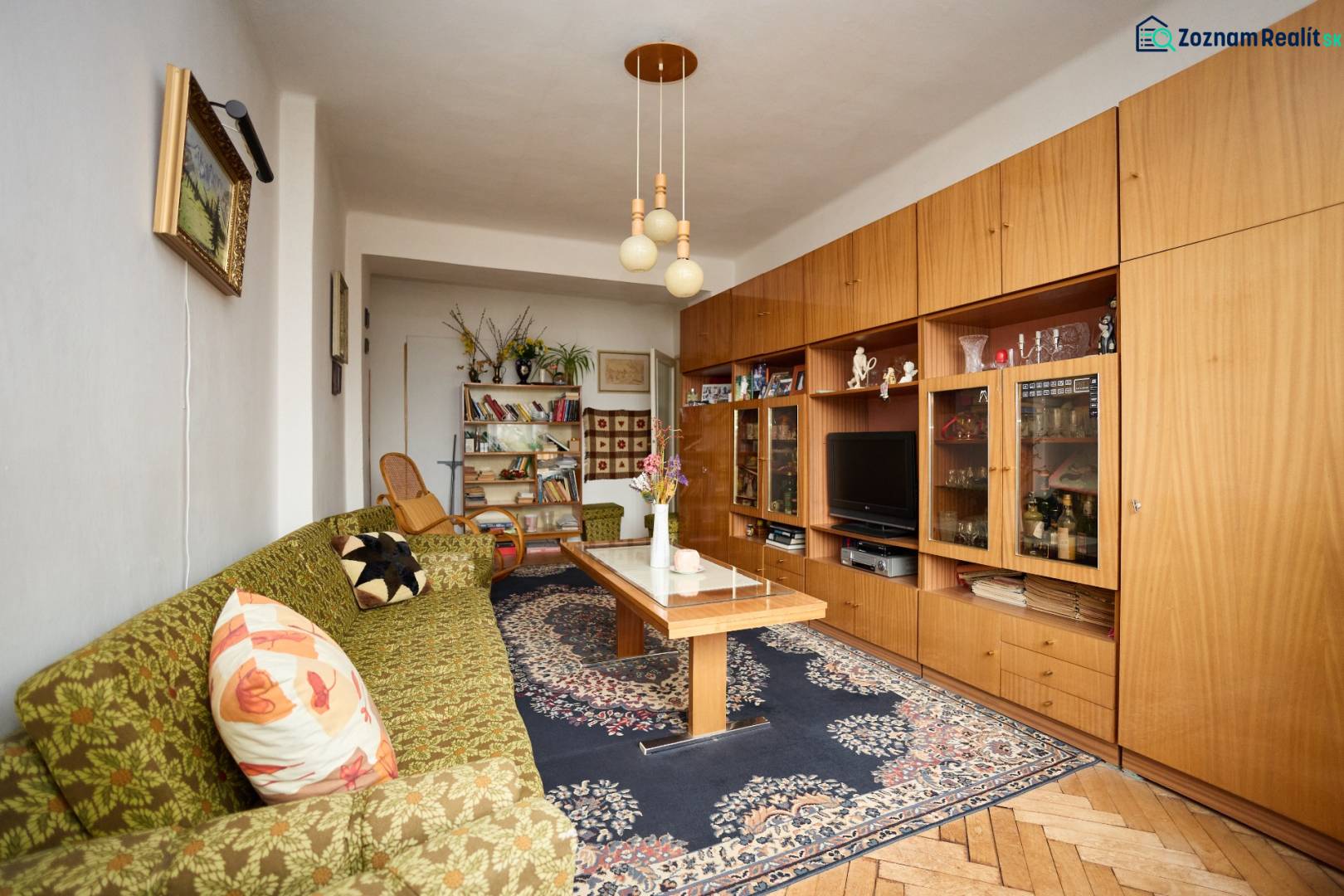 Obývací pokoj v 3-pokojovém bytě s kobercem a podlahou s dřevěným dekorem.