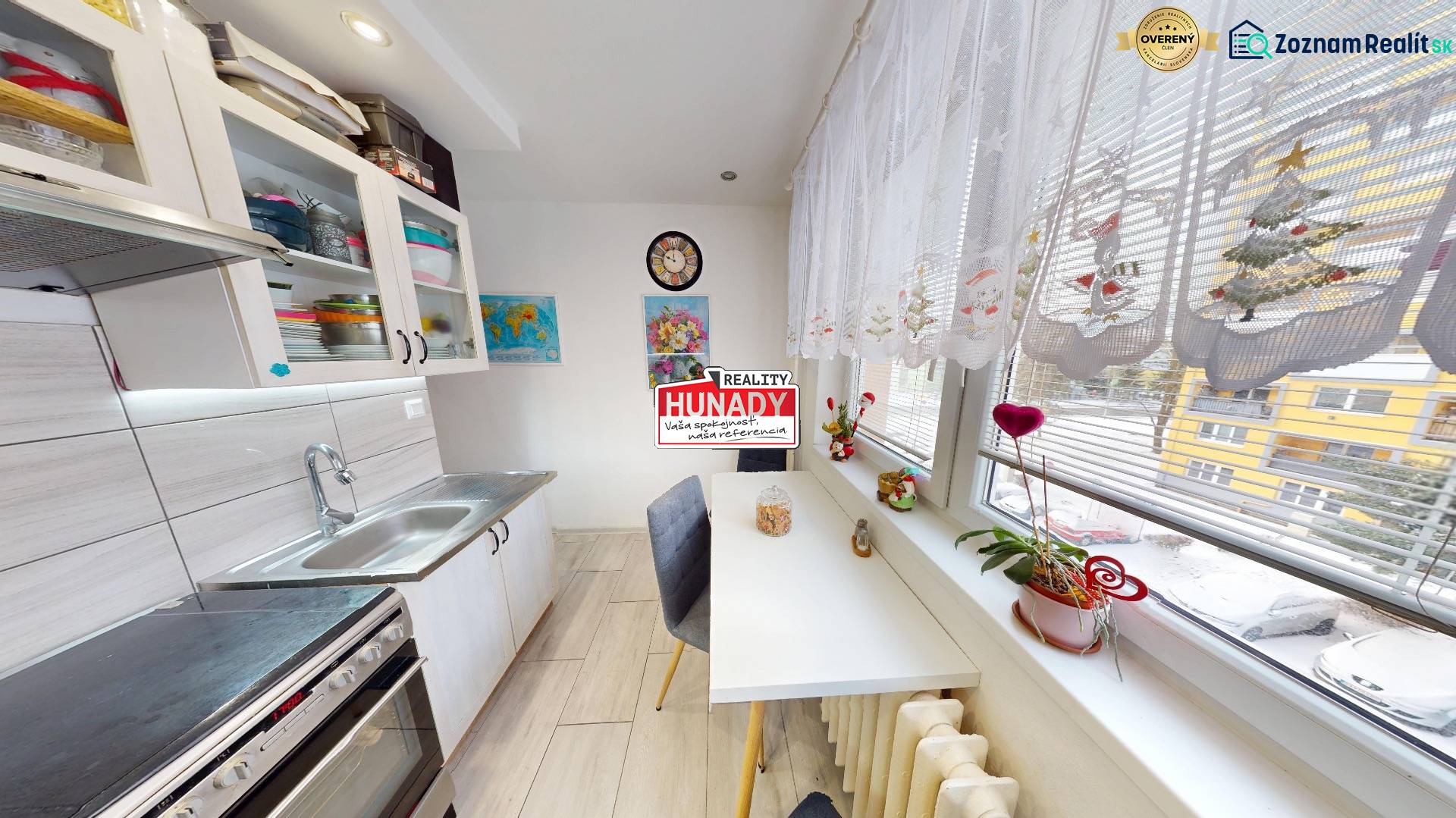 Kuchyně v 2pokojovém bytě se světlými skříňkami, jídelním stolem a velkými okny.