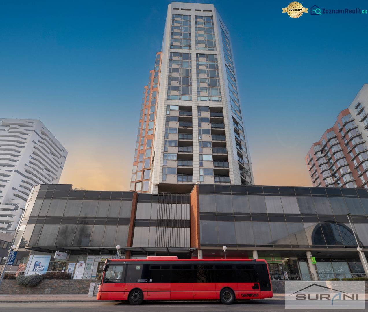 Bytový dům na Kopčianské ulici v Bratislavě - Petržalce s červeným autobusem před ním.