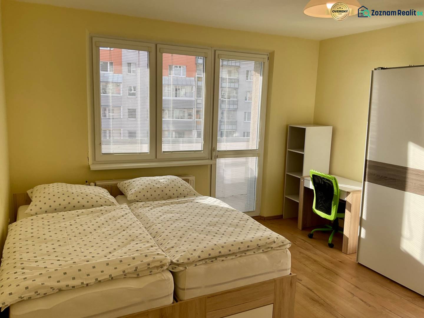 Ložnice s manželskou postelí, pracovním stolem a podlahou s dřevěným dekorem v 3-pokojovém bytě.