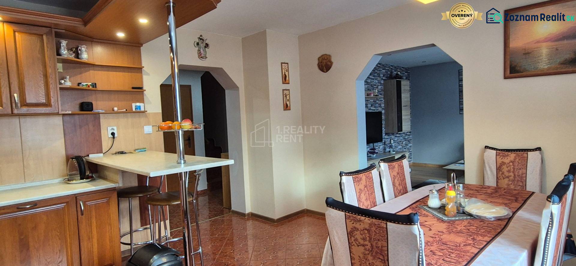 Jídelna v rodinném domě s dřevěnými prvky, stolem a židlemi, světlý interiér.