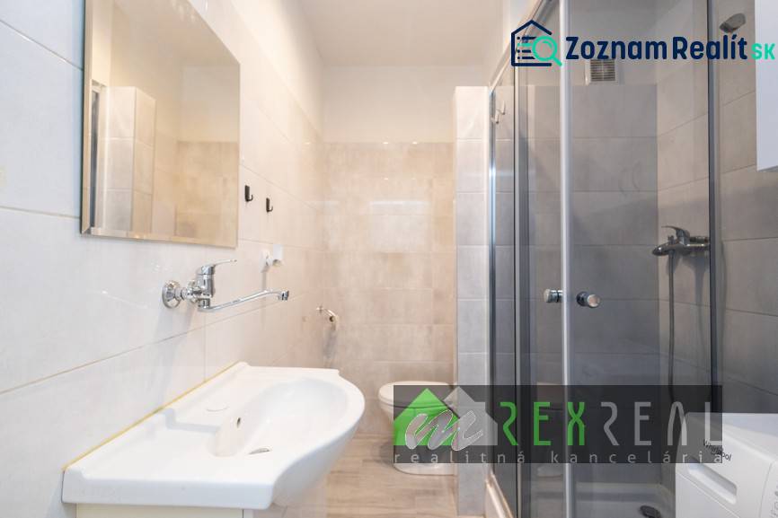 Koupelna v 3-pokojovém bytě se sprchovým koutem, umyvadlem a světlými dlaždicemi.