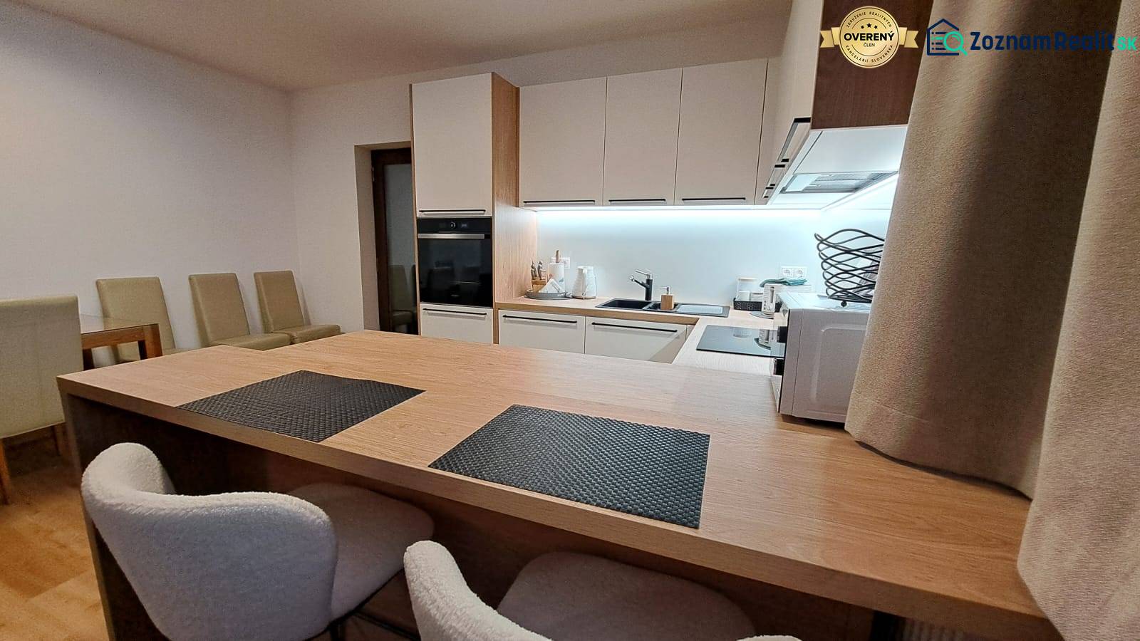 Kuchyně v 2pokojovém bytě s vestavěnými spotřebiči a podlahou s dřevěným dekorem.