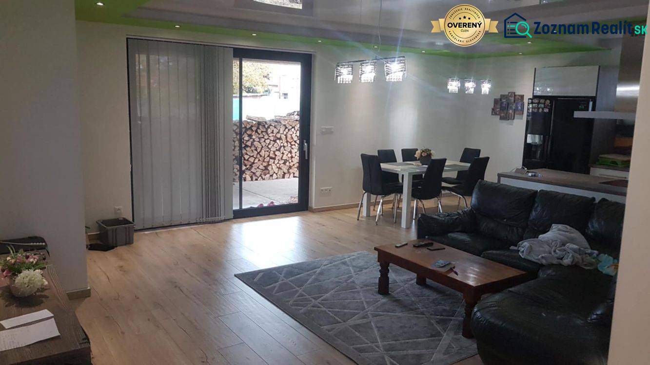 Obývací pokoj v rodinném domě s podlahou s dřevěným dekorem, pohovkou a jídelním stolem.