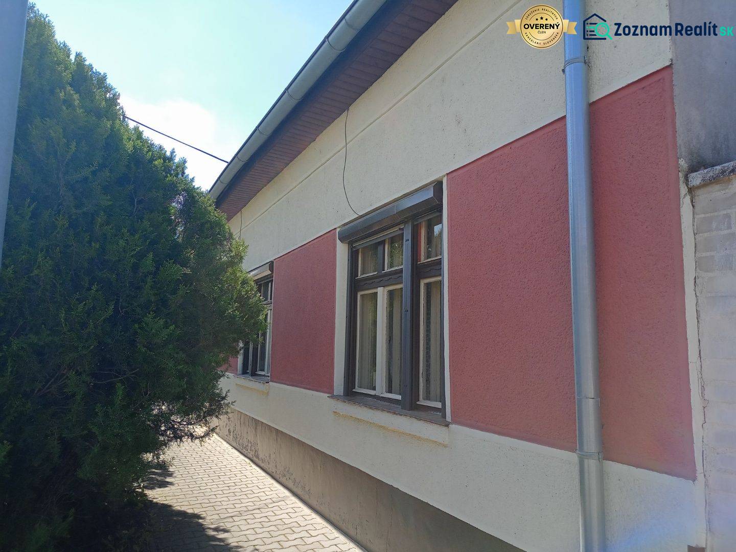 Rodinný dům v Nových Zámcích se sítěmi na zateplené fasádě a stromem u chodníku.