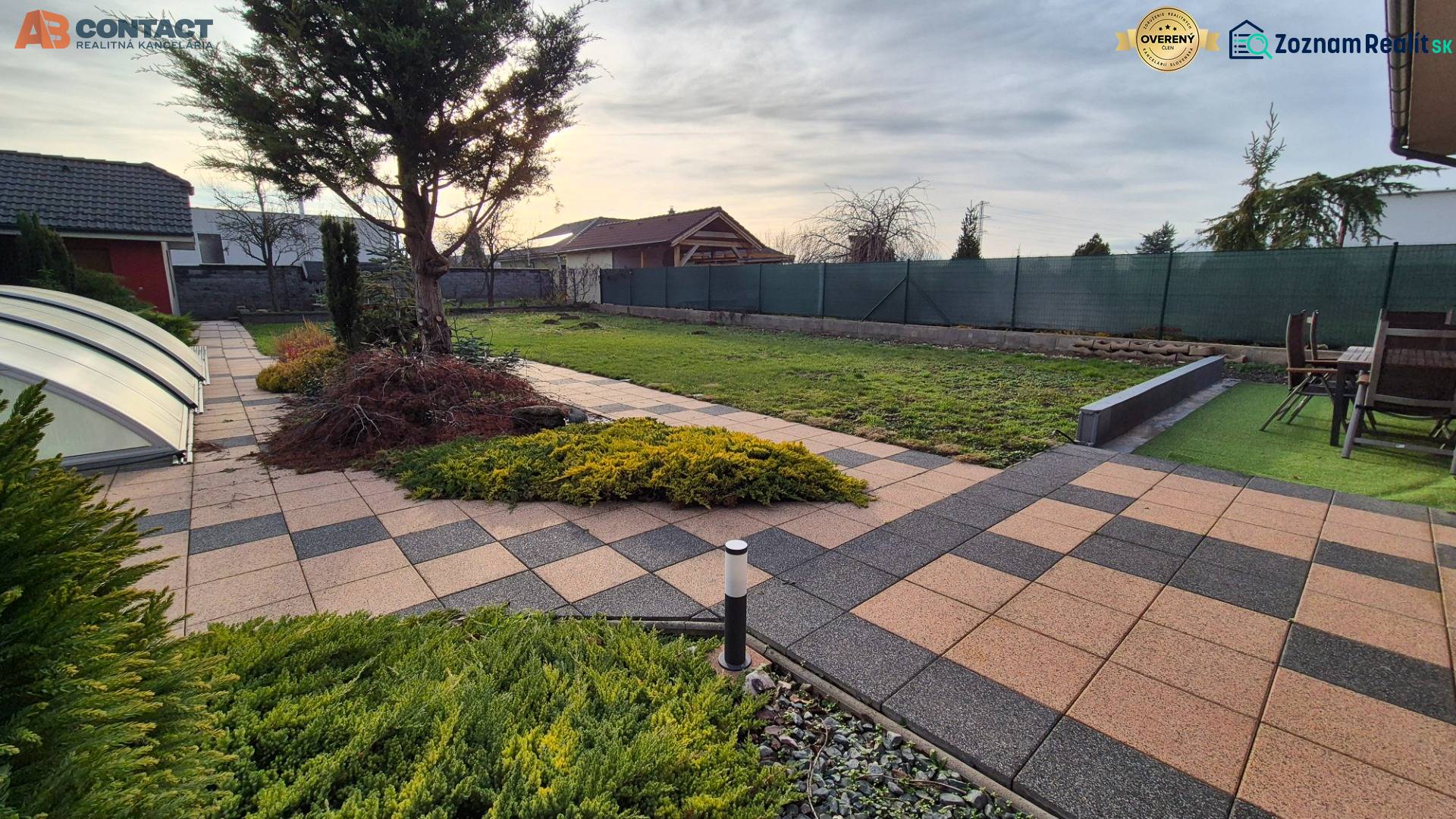 Zahrada u rodinného domu na Větrné ulici v Krakovanech s dlažbou a terasou.