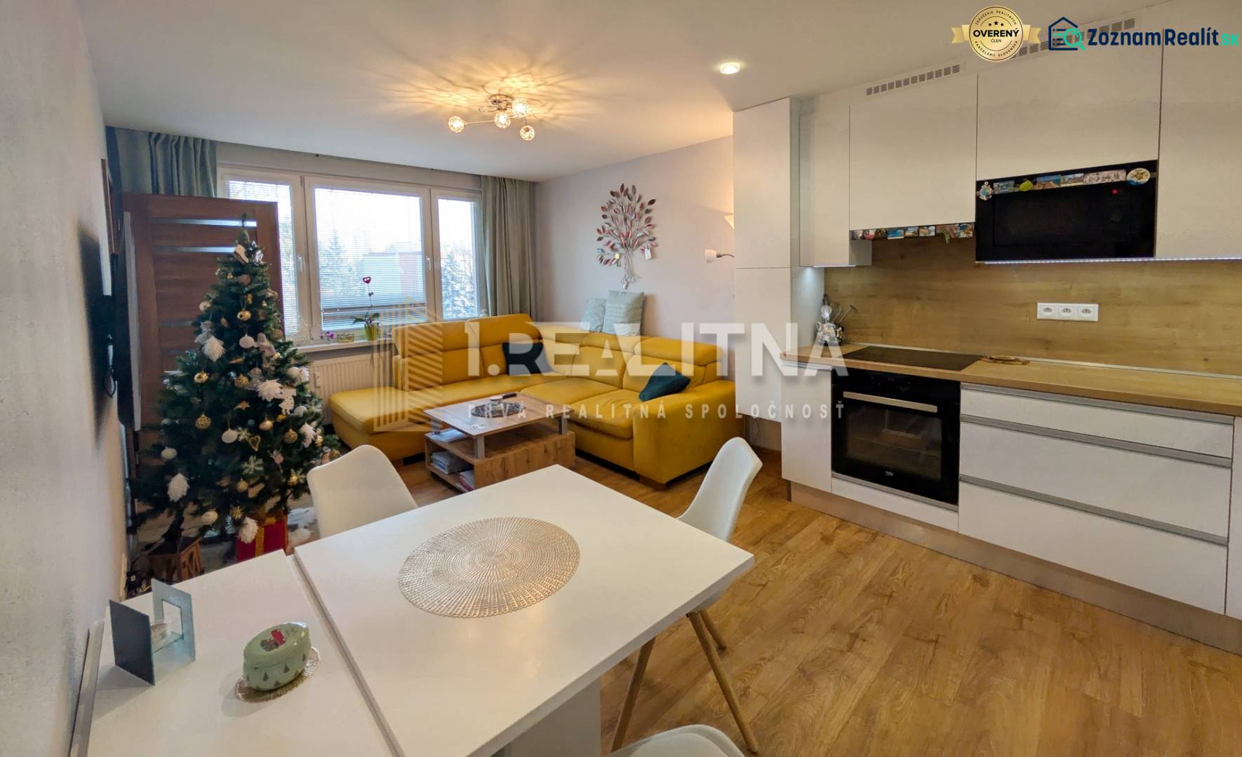 Obývací pokoj v 3pokojovém bytě s podlahou s dřevěným dekorem a kuchyní.