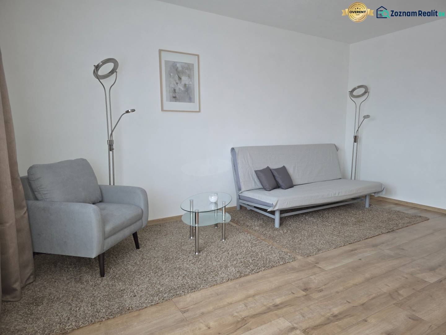 Obývací pokoj s křeslem, pohovkou a podlahou s dřevěným dekorem ve 3-pokojovém bytě.