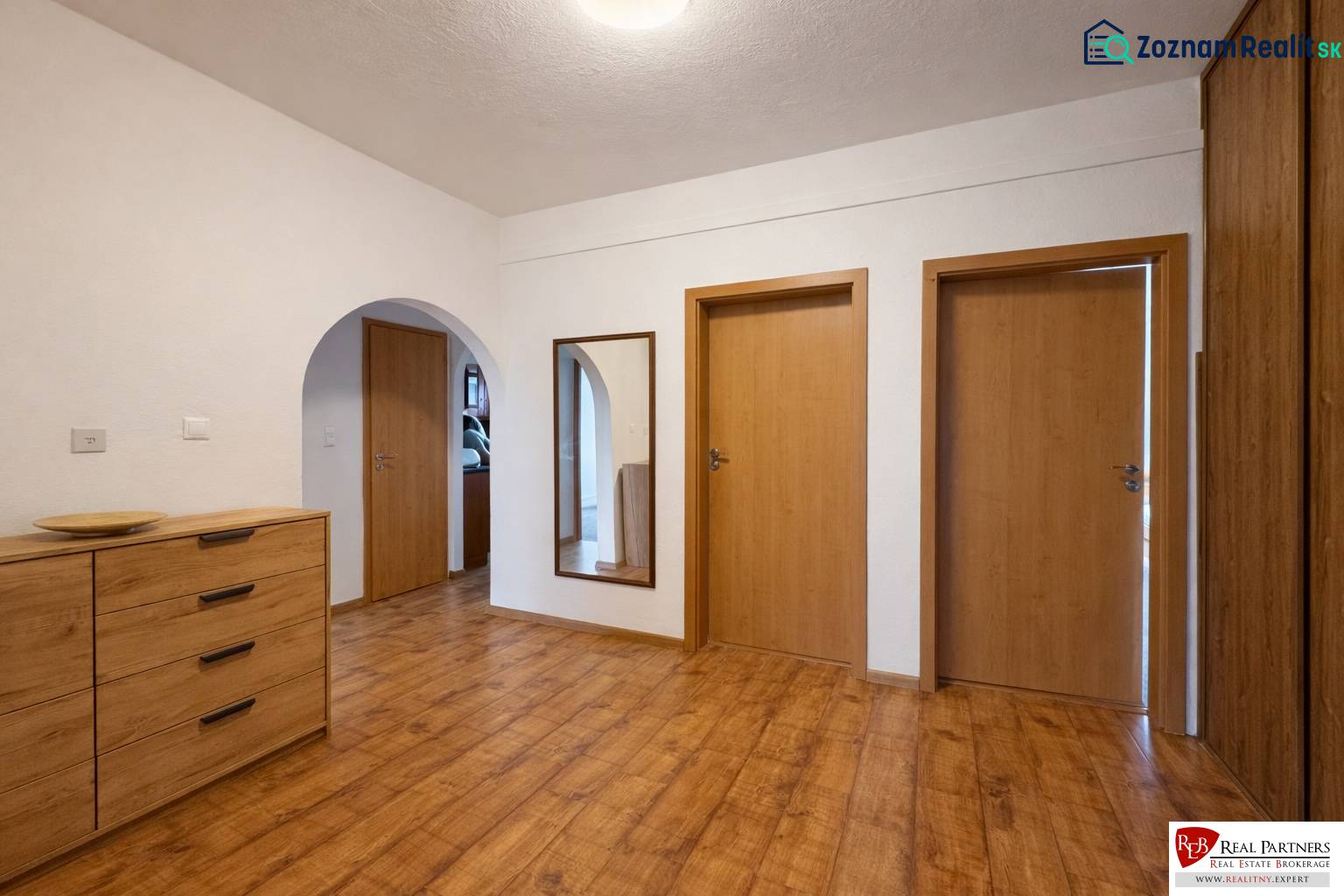 Chodba s podlahou s dřevěným dekorem a dřevěnými dveřmi ve 4pokojovém bytě.