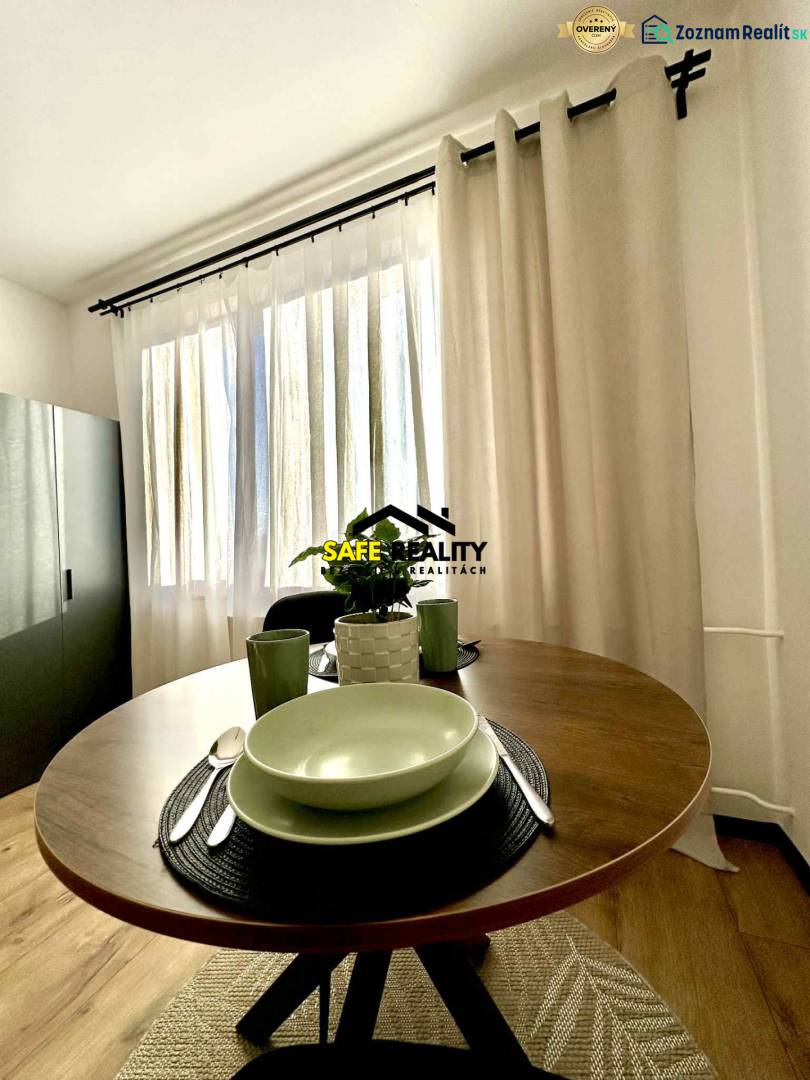 Jeden útulný kout 1-pokojového bytu s kulatým stolem a nádobím.