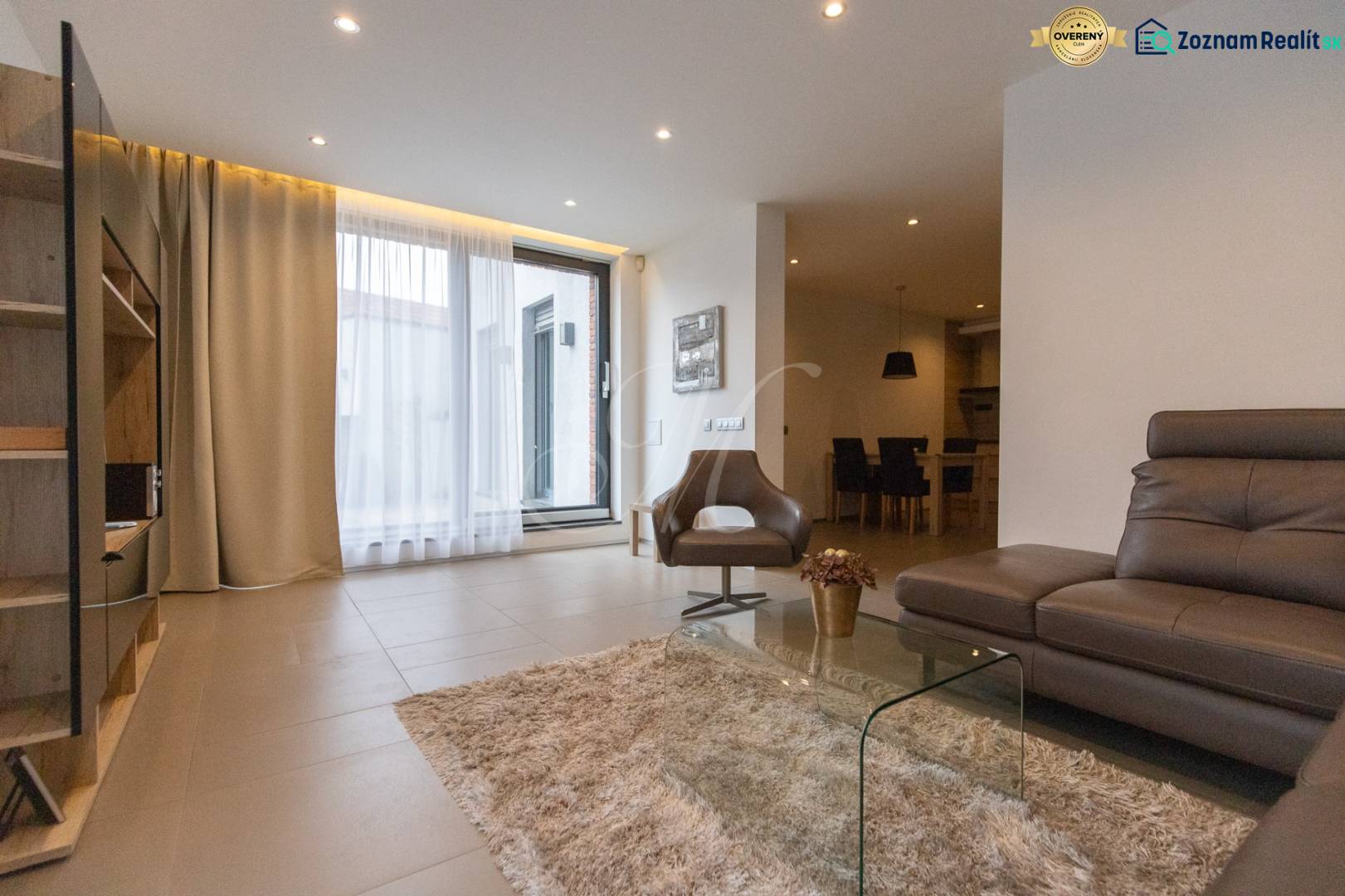 Obývací pokoj v 2-pokojovém bytě s pohodlnou sedačkou, křeslem a skleněným stolkem.