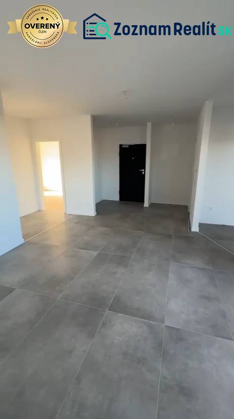 Interiér 3-pokojového bytu s velkými dlaždicemi a bílými stěnami.