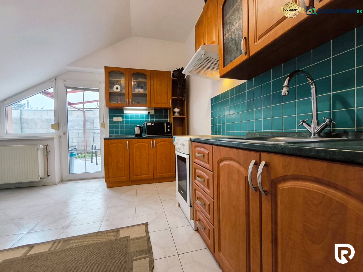 Kuchyně s dřevěnými skříňkami a zeleným obkladem v rodinném domě.