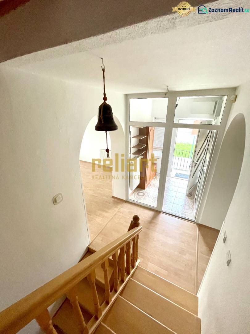 Schodiště s podlahou s dřevěným dekorem, vstupní dveře a zvonek v rodinném domě.