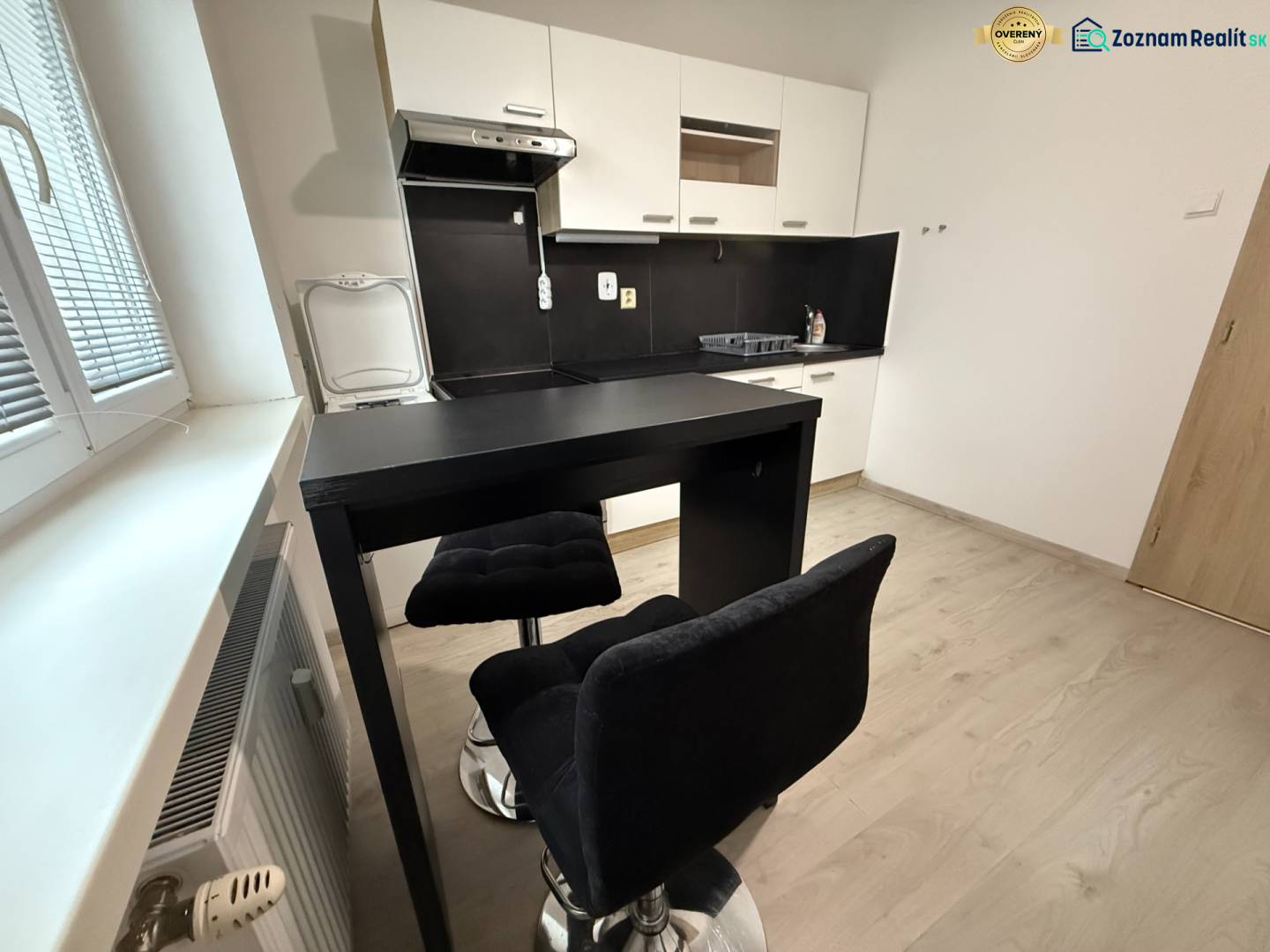 Kuchyně s posezením a podlahou s dřevěným dekorem v 1-pokojovém bytě.