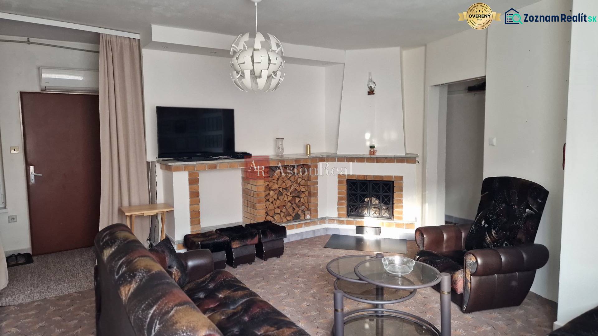 Obývací pokoj s krbem v rodinném domě, kožené křeslo a konferenční stolek.