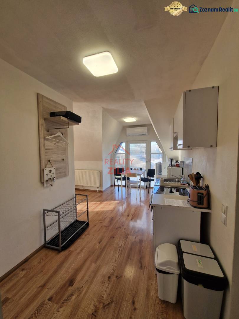 Interiér rodinného domu s kuchyní a jídelním koutem, podlaha s dřevěným dekorem.