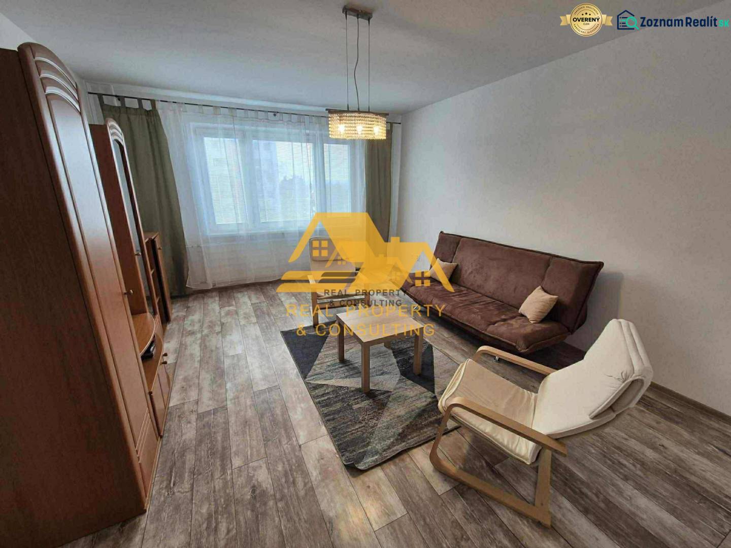 Obývací pokoj v 3-pokojovém bytě s pohovkou, křeslem a podlahou s dřevěným dekorem.