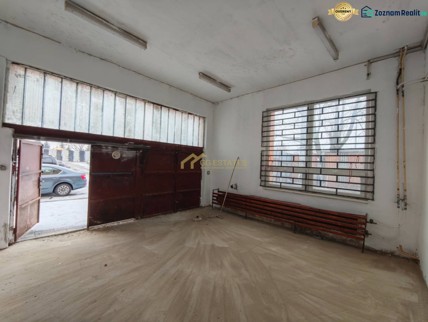 Interiér garáže s podlahou s dřevěným dekorem a kovovou bránou.