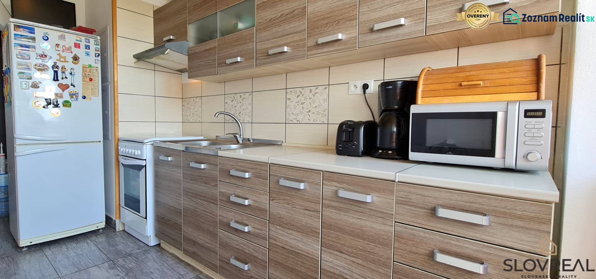 Kuchyně v 2pokojovém bytě s podlahou s dřevěným dekorem a spotřebiči.