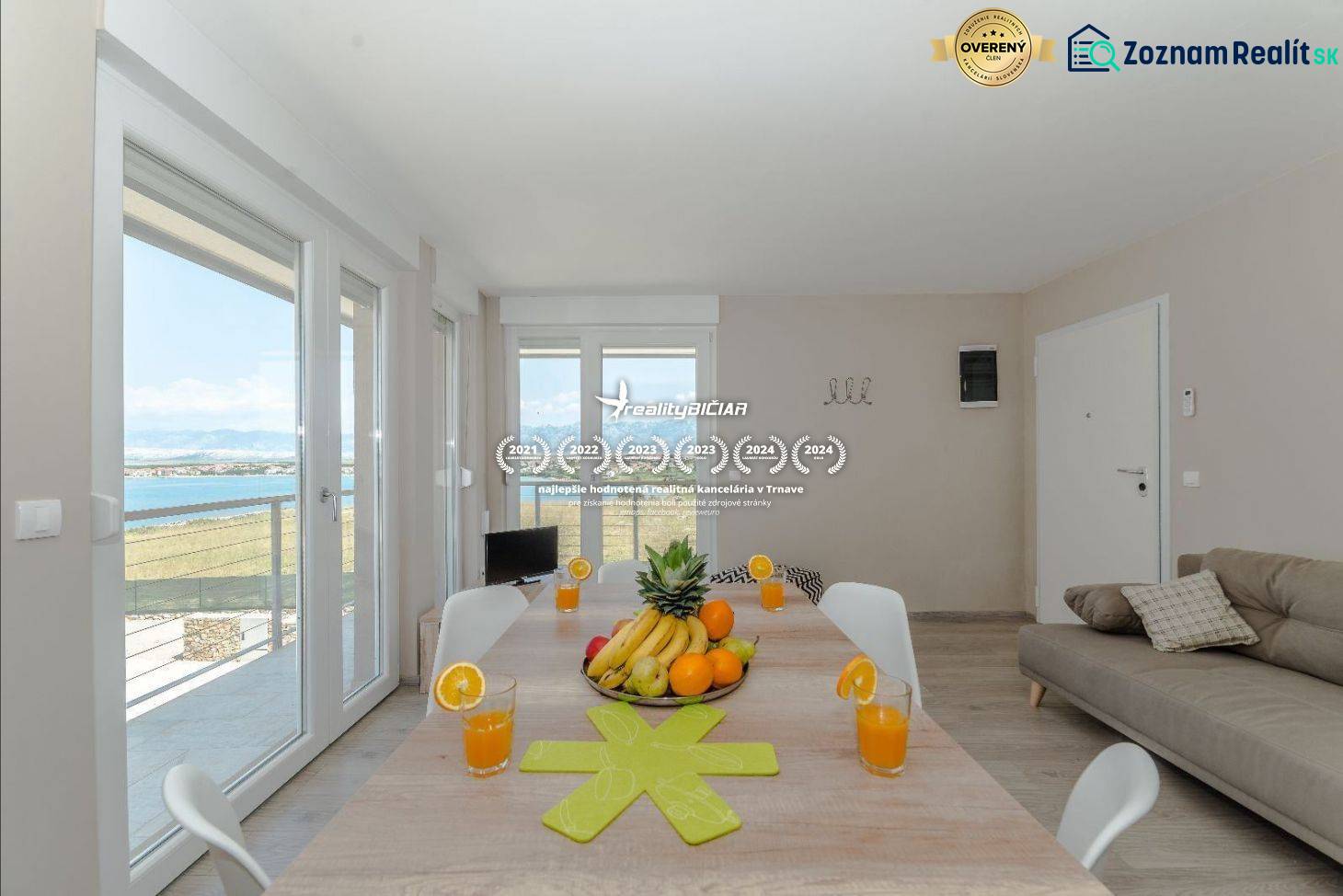 Jídelní stůl v rekreačním apartmánu s výhledem na moře přes velká okna.