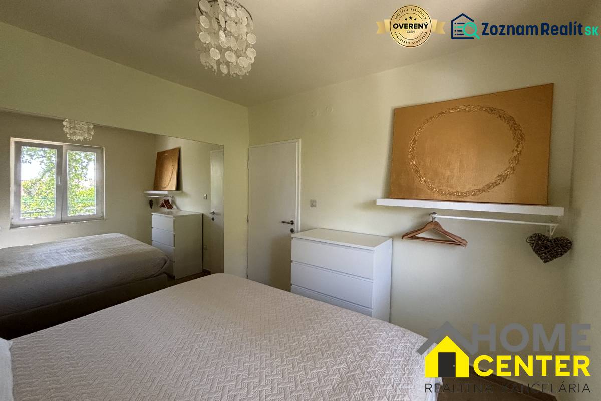 Ložnice v rodinném domě s bílým nábytkem, zrcadlem a texturovanými přehozy na postel.