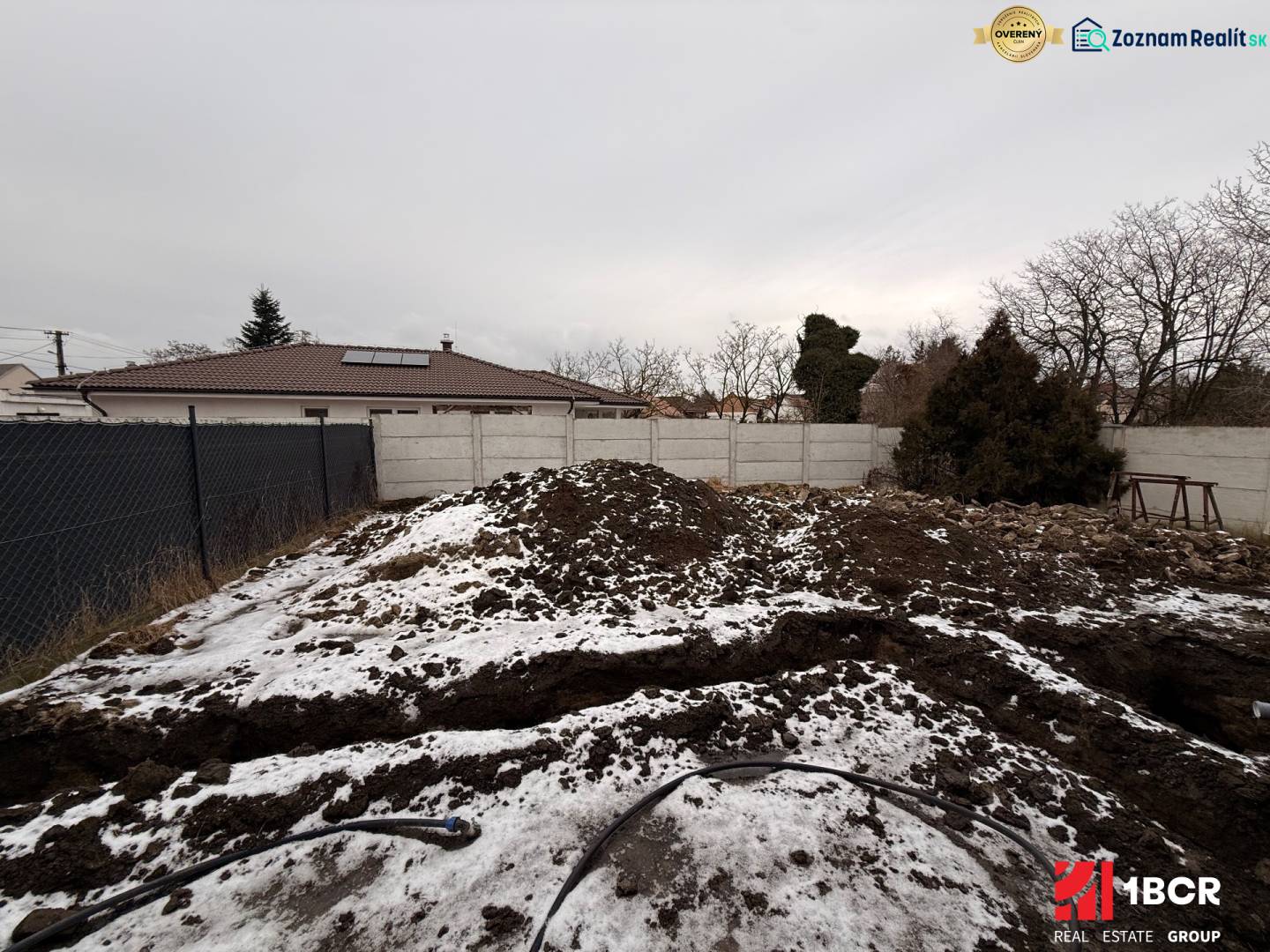 Staveniště rodinného domu v Senci během zimního období s plotem a sněhem.