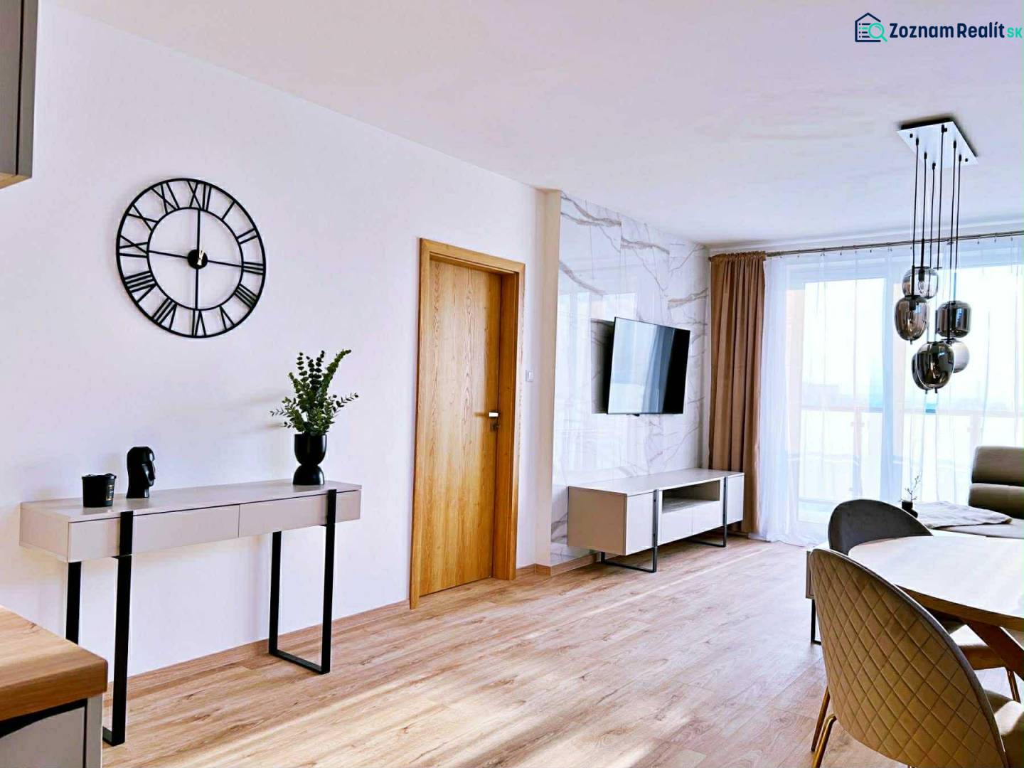 Obývací pokoj ve 3pokojovém bytě s podlahou s dřevěným dekorem, stolem a televizí.