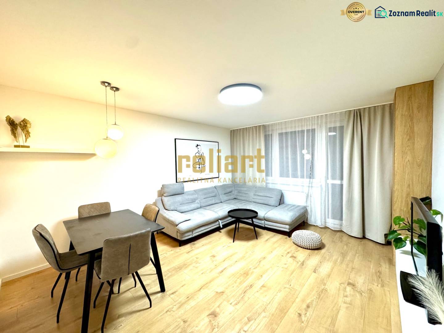 Obývací pokoj ve 3-pokojovém bytě s podlahou s dřevěným dekorem, sedačkou a jídelním stolem.