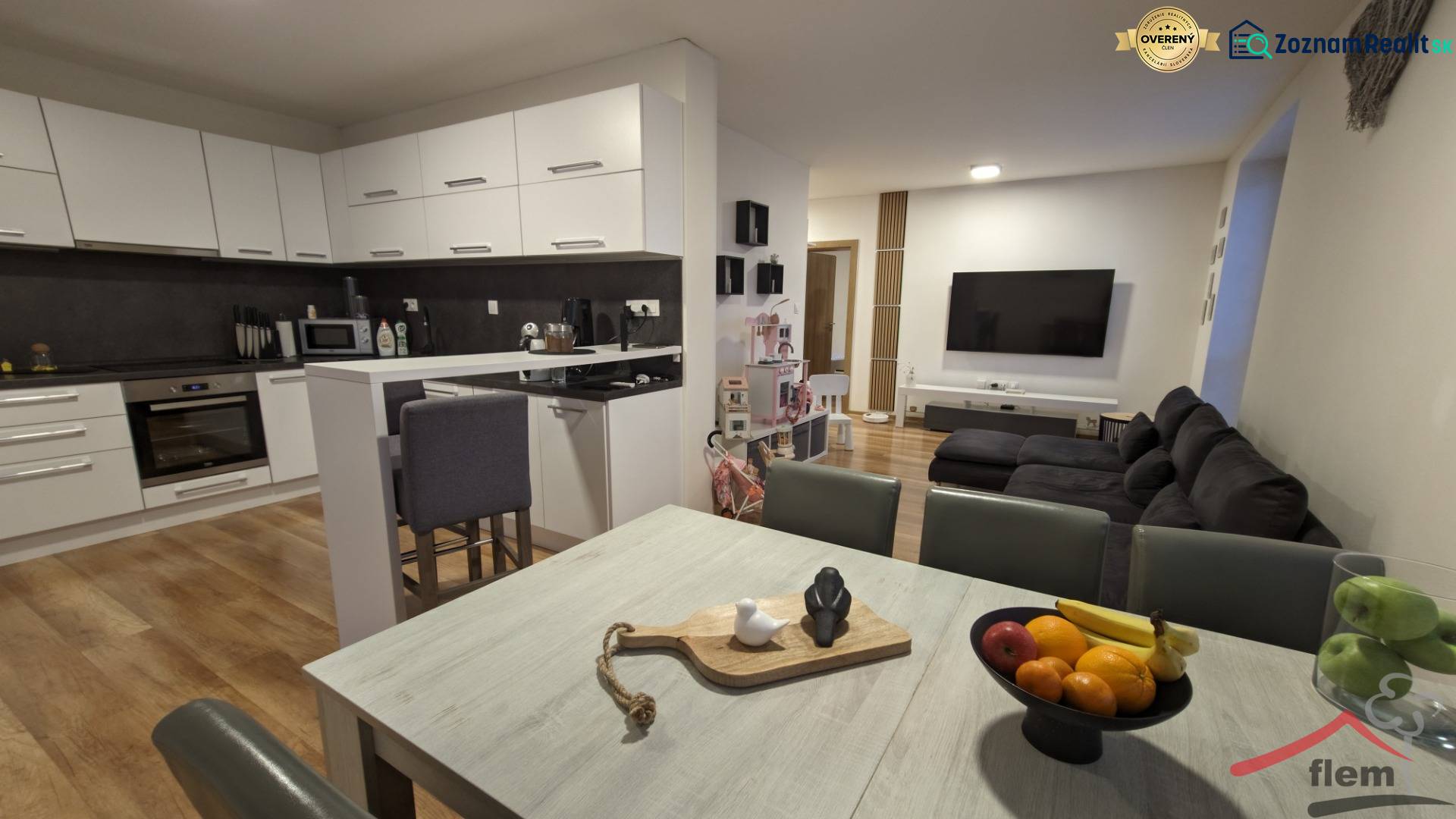 Kuchyně s obývacím pokojem ve 2-pokojovém bytě, světlá linka, podlaha s dřevěným dekorem.
