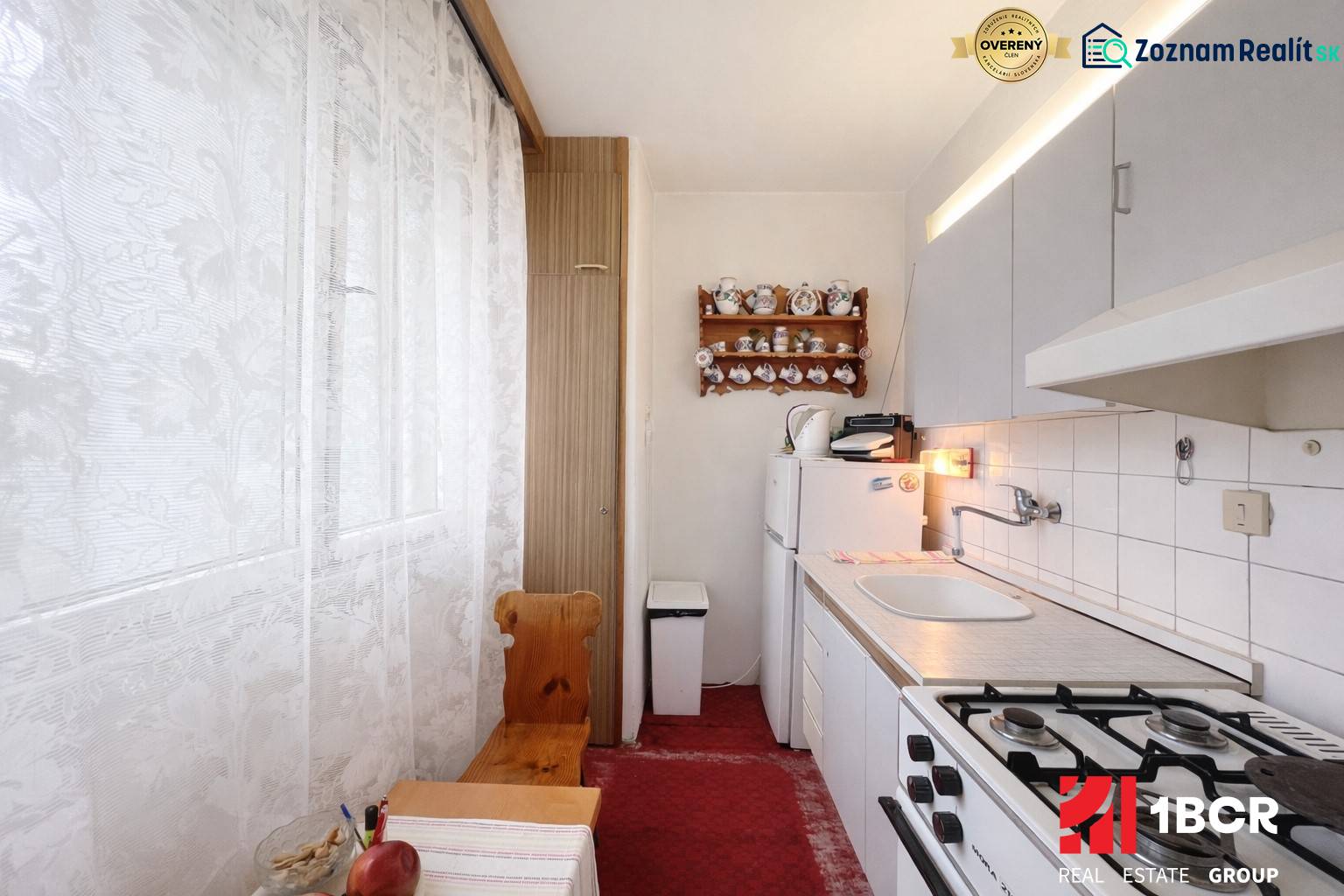 Útulná kuchyně s plynovým sporákem a rustikální dekorací v 1-pokojovém bytě.