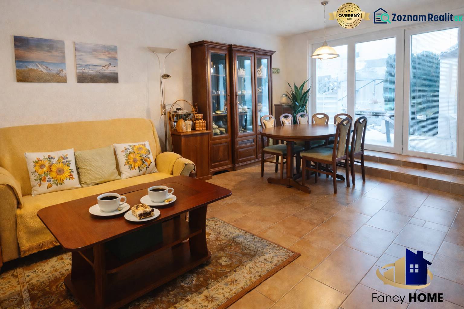 Obývací pokoj v rodinném domě s jídelním stolem, policemi a pohovkou.