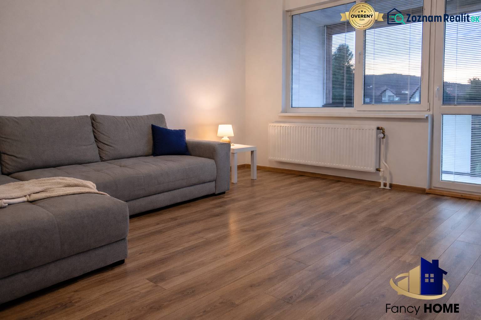 Obývací pokoj v 3pokojovém bytě s pohovkou a podlahou s dřevěným dekorem.