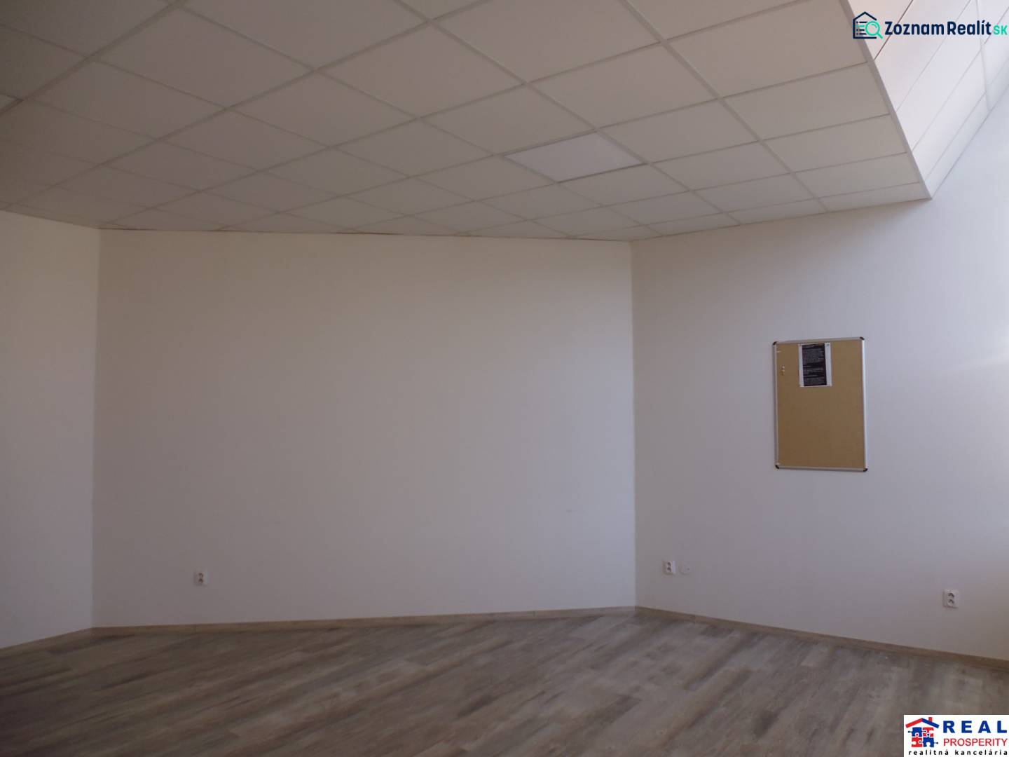 Místnost s podlahou s dřevěným dekorem a korkovou nástěnkou v kanceláři.