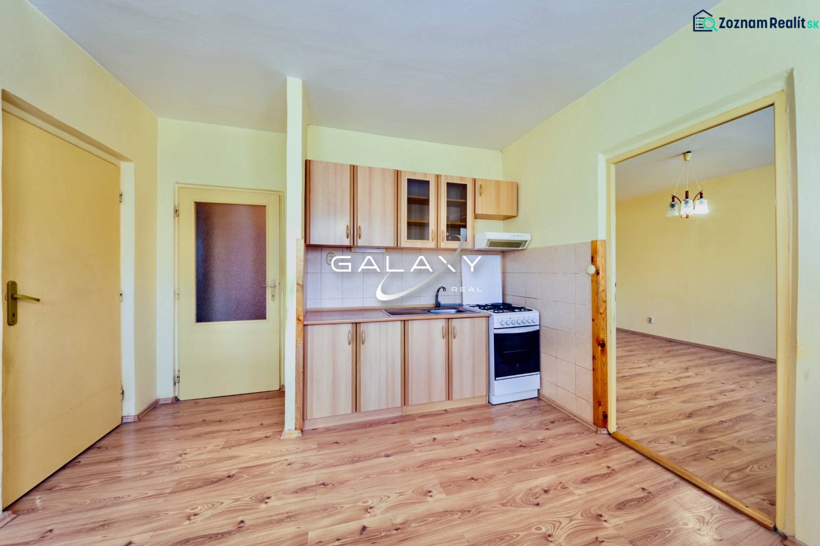 Kuchyně v 1-pokojovém bytě s podlahou s dřevěným dekorem a plynovým sporákem.