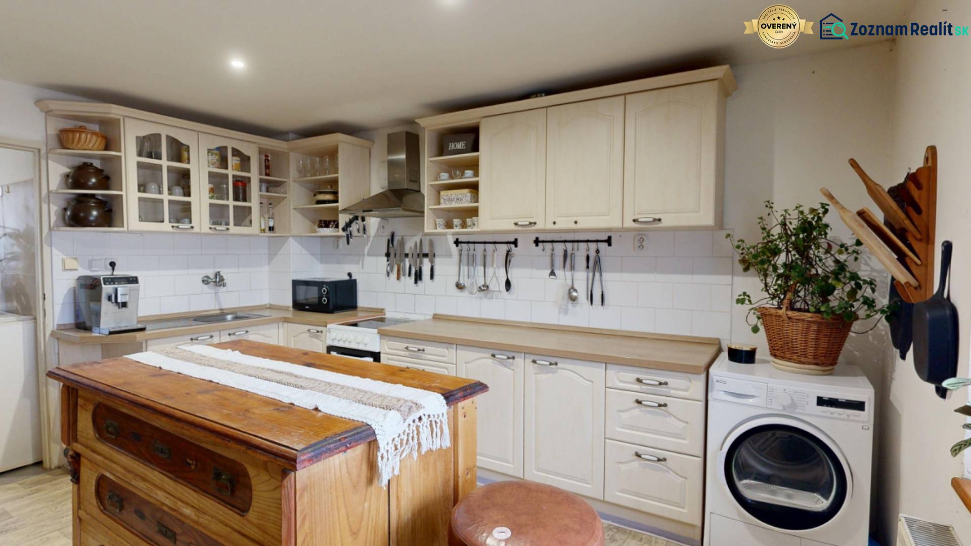 Kuchyně s vintage ostrovem, kuchyňskými skříňkami, dřezem a pračkou v rodinném domě.