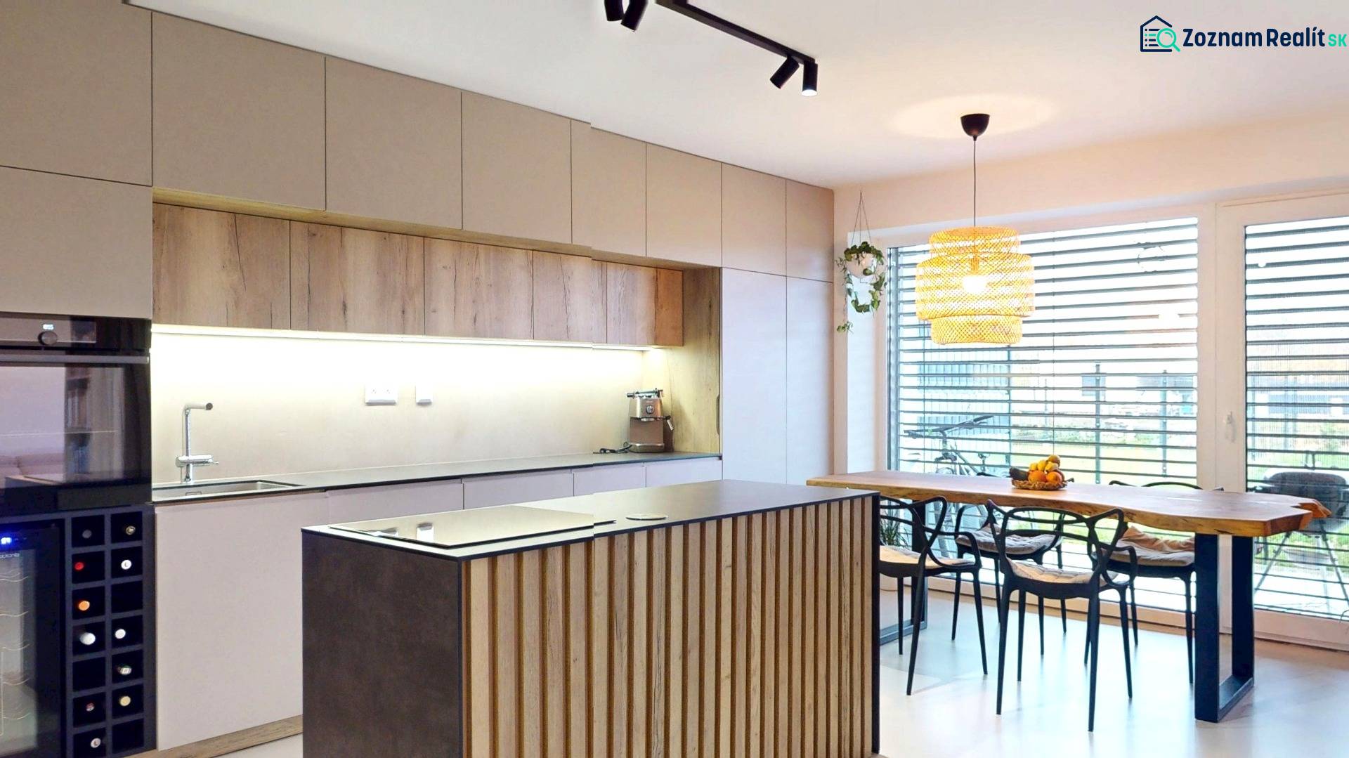 Kuchyně v rodinném domě s dřevěným dekorem nábytku a velkými okny.