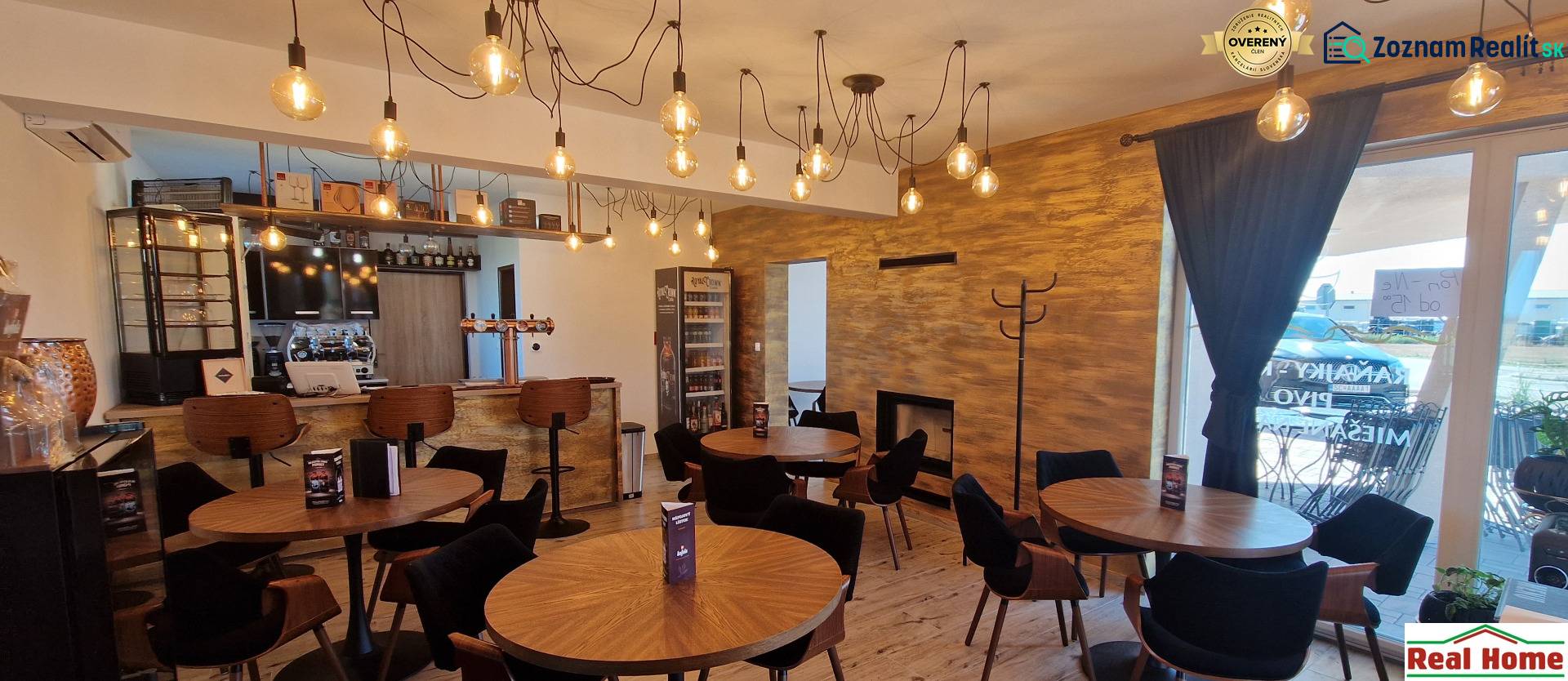 Gastro prostory s visícími světly, dřevěným dekorem a útulným sezením.