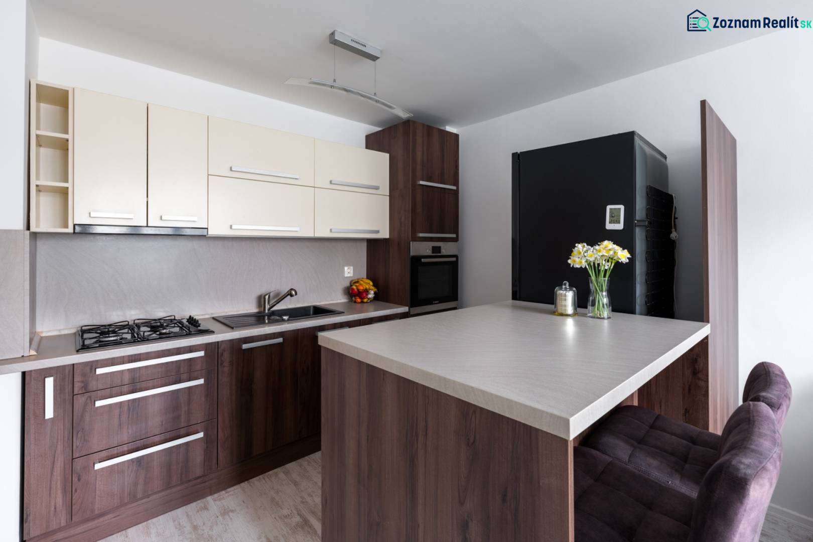 Kuchyně v 2-pokojovém bytě s podlahou s dřevěným dekorem, barovým pultem a moderním vybavením.