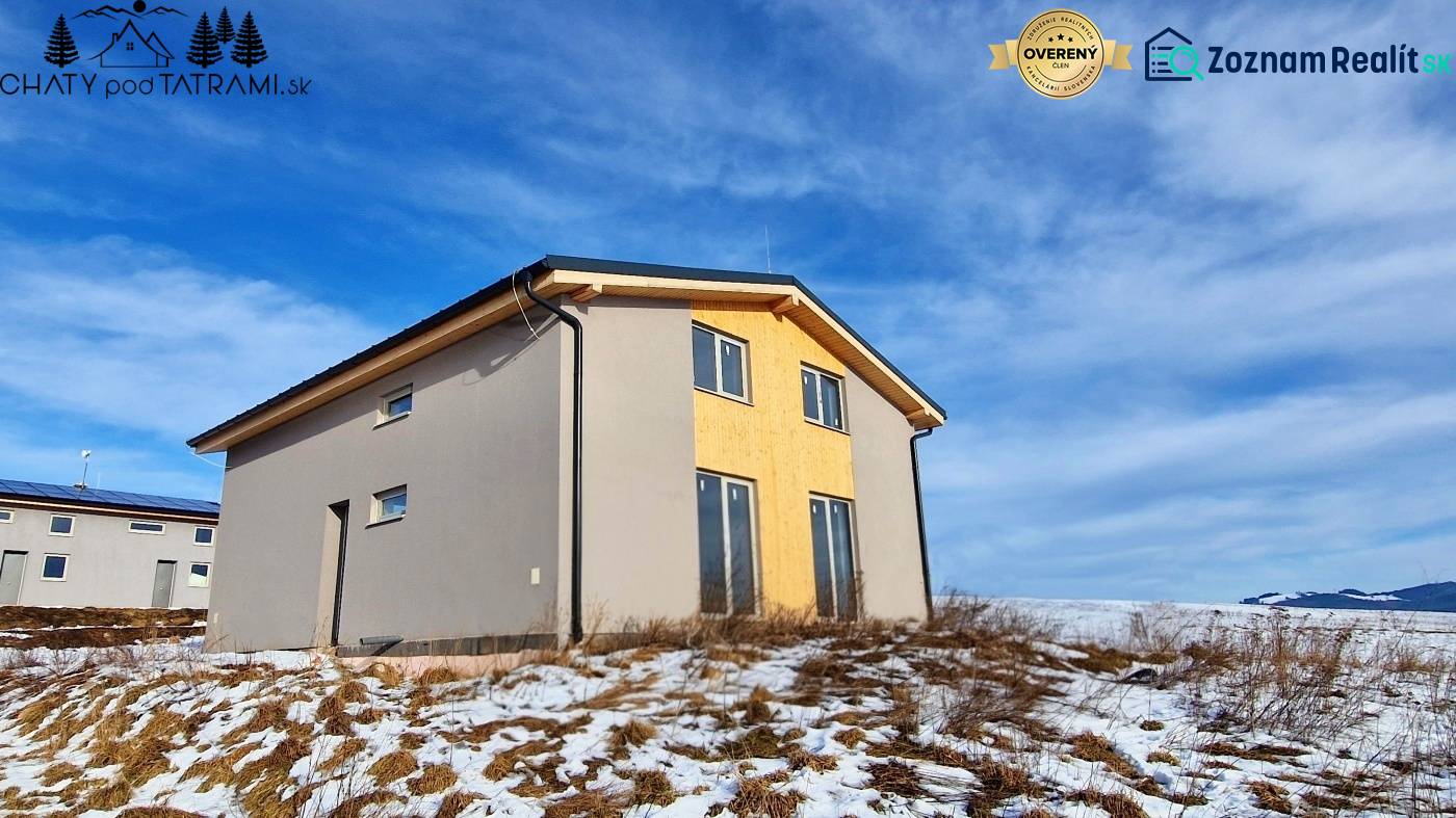 Chata v Dolní Lehotě s dřevěným dekorem, zasněžený pozemek a zamračená obloha.