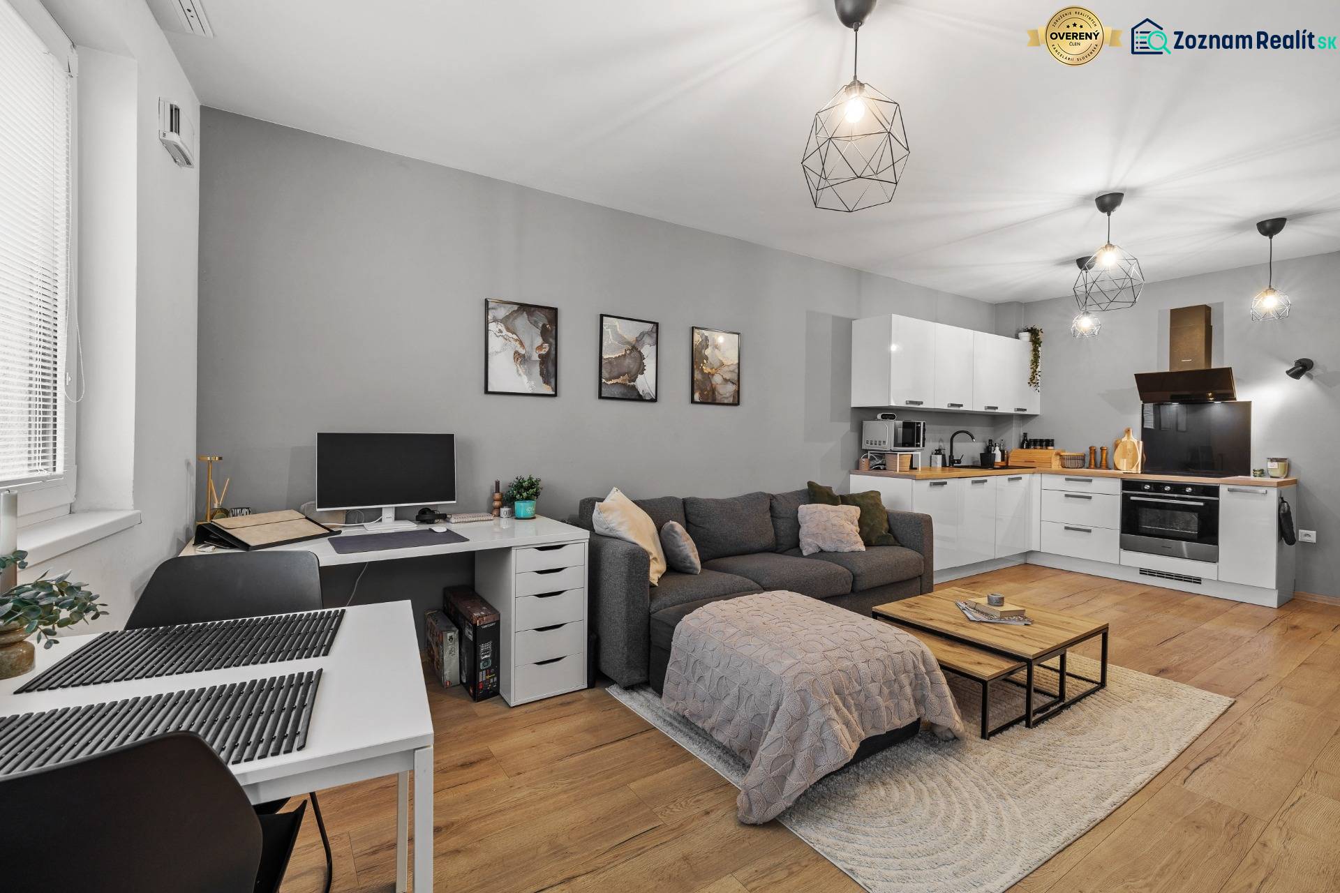 Obývací pokoj v 2pokojovém bytě s kuchyní, rozkládací pohovkou a podlahou s dřevěným dekorem.