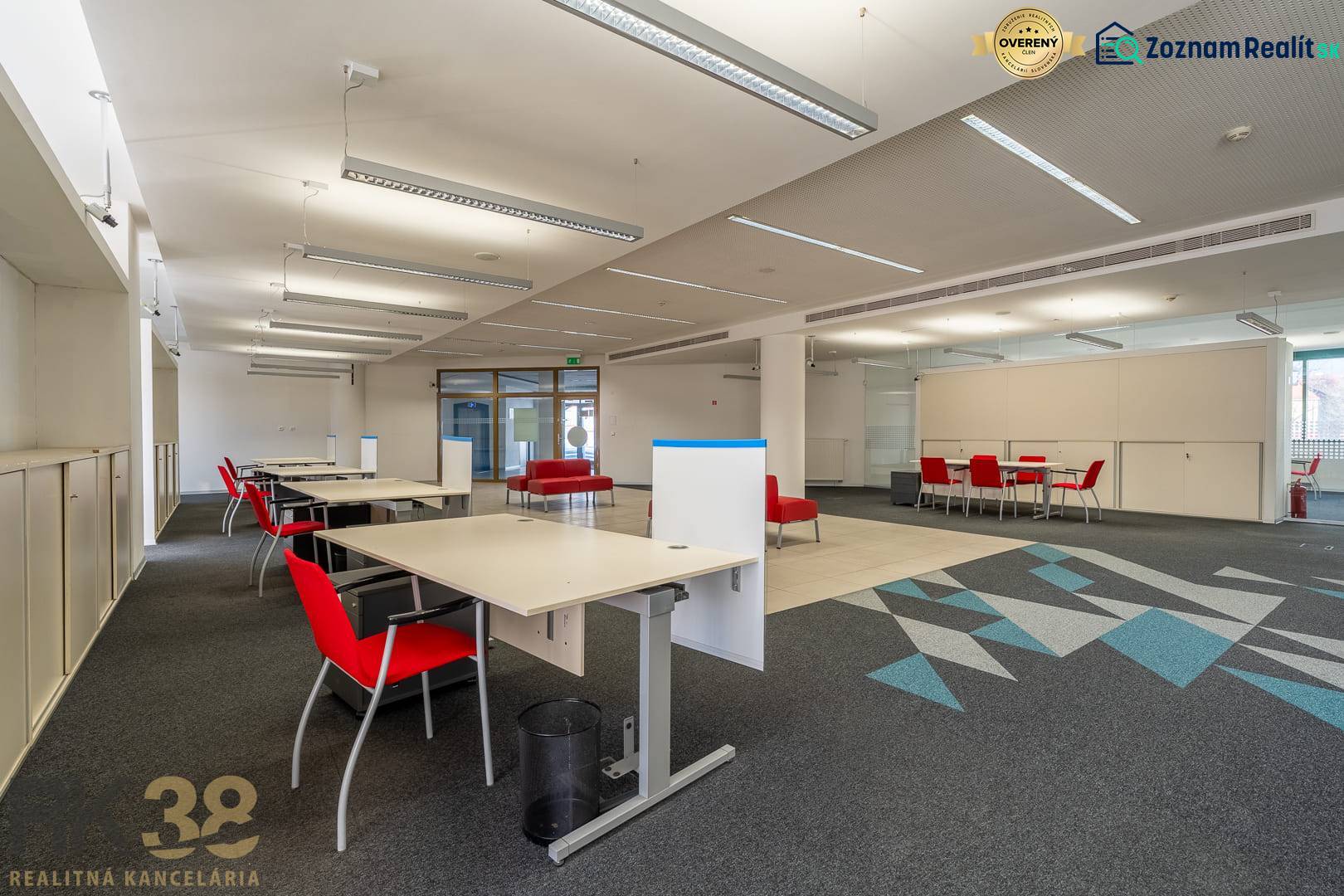Interiér kanceláří s červenými židlemi a kobercovou dekorací na podlaze.
