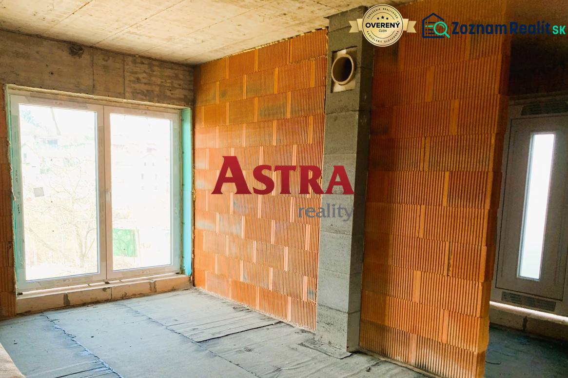 Nedokončený interiér budovy se surovými cihlami a velkými okny přináší potenciál útulné chaty.