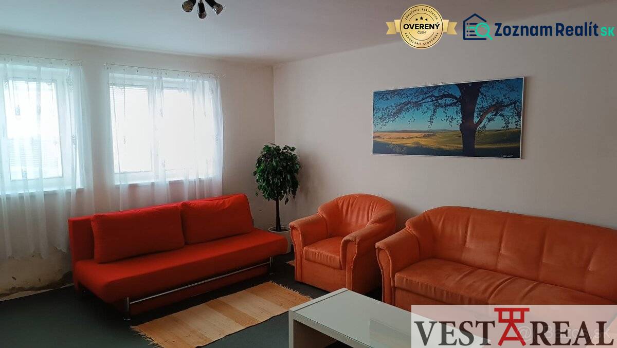 Obývací pokoj v rodinném domě s oranžovou sedačkou, křesly a obrazem krajiny.